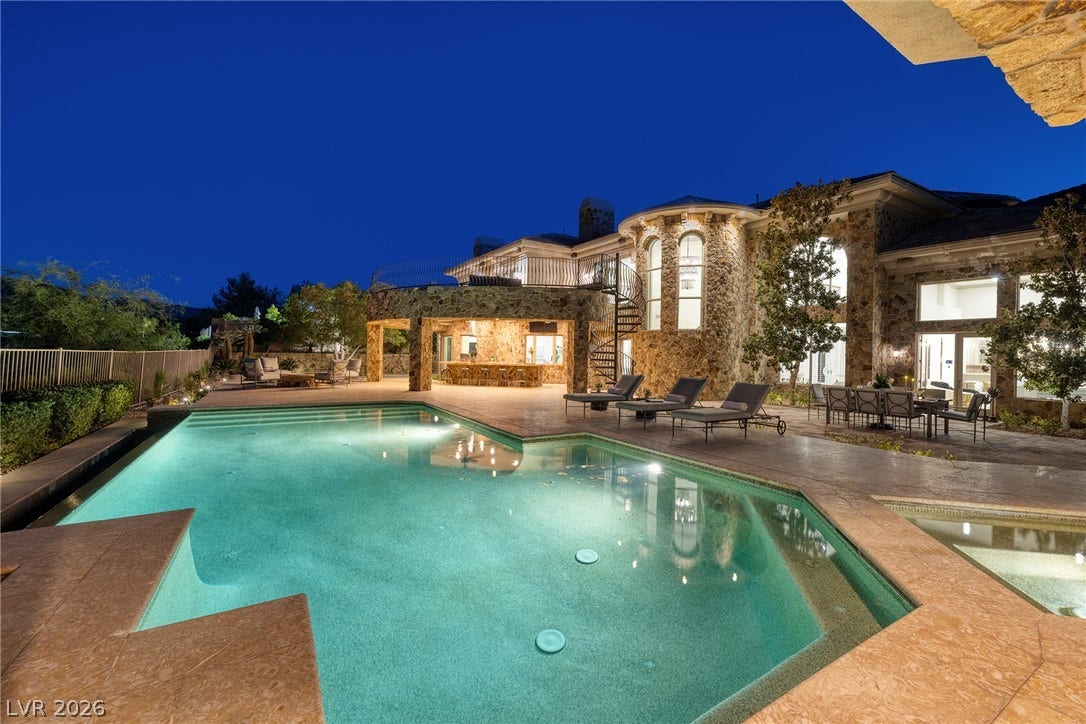 4 Ayden Drive, Henderson, NV 89052 An inviting swimming pool and stone terrace sit beneath the illuminated facade of this estate.