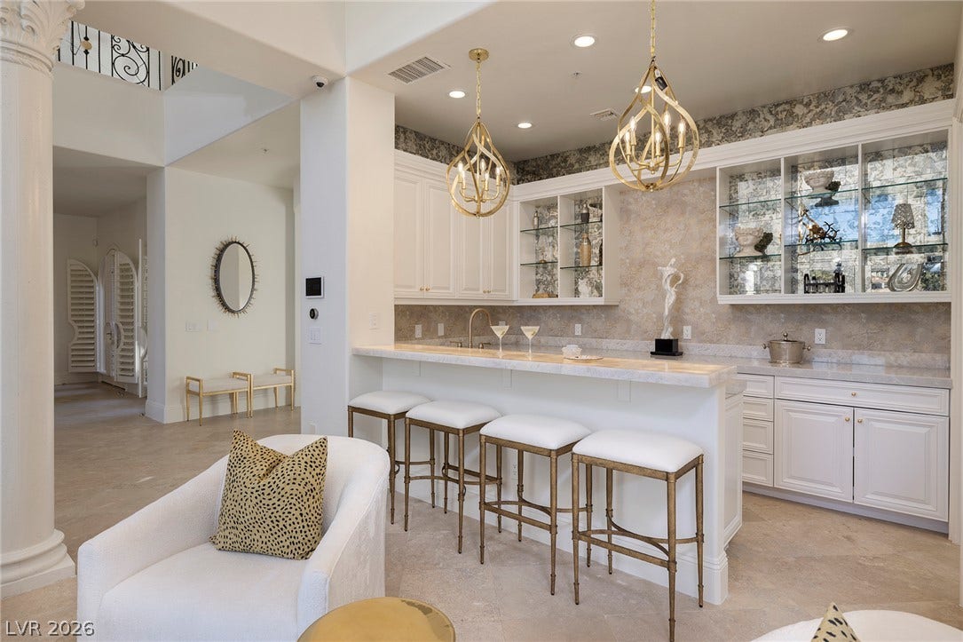 4 Ayden Drive, Henderson, NV 89052 An elegant home bar features custom cabinetry, stone countertops, and elevated architectural detailing.