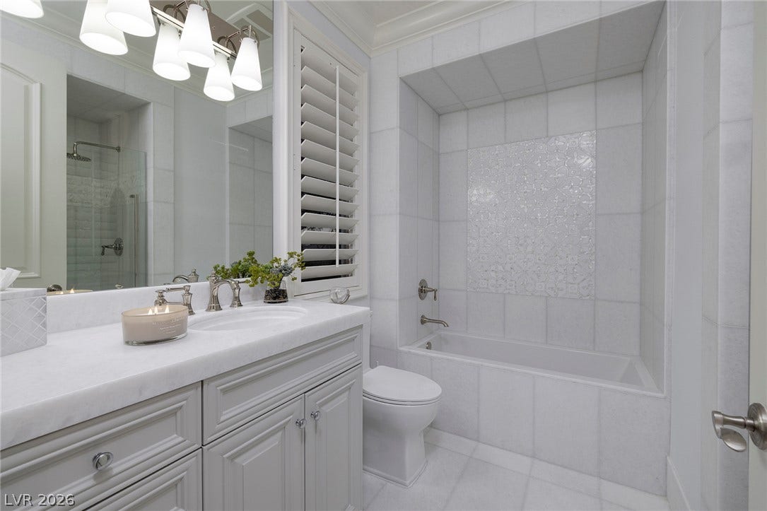 4 Ayden Drive, Henderson, NV 89052 Floor-to-ceiling tile work and plantation shutters highlight this bathroom with a built-in tub.