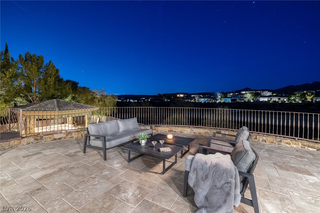 4 Ayden Drive, Henderson, NV 89052 An expansive stone patio overlooks scenic valley lights under a clear night sky.