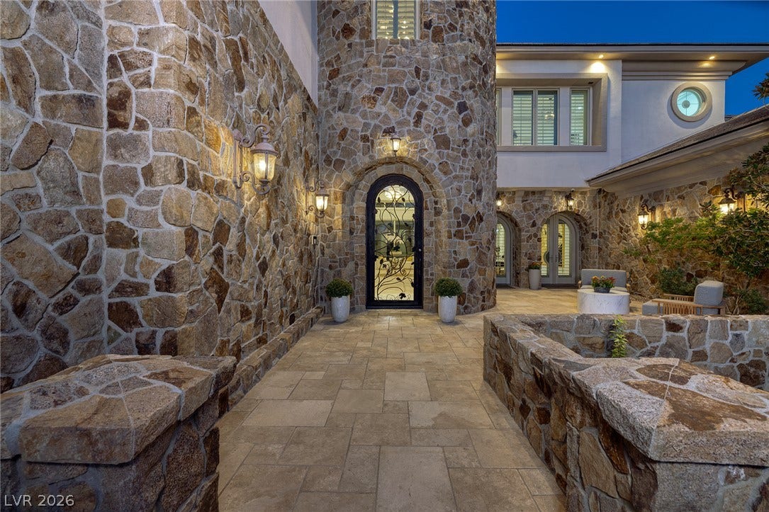 4 Ayden Drive, Henderson, NV 89052 A grand stone pathway leads to an arched glass entrance door under elegant exterior lighting.