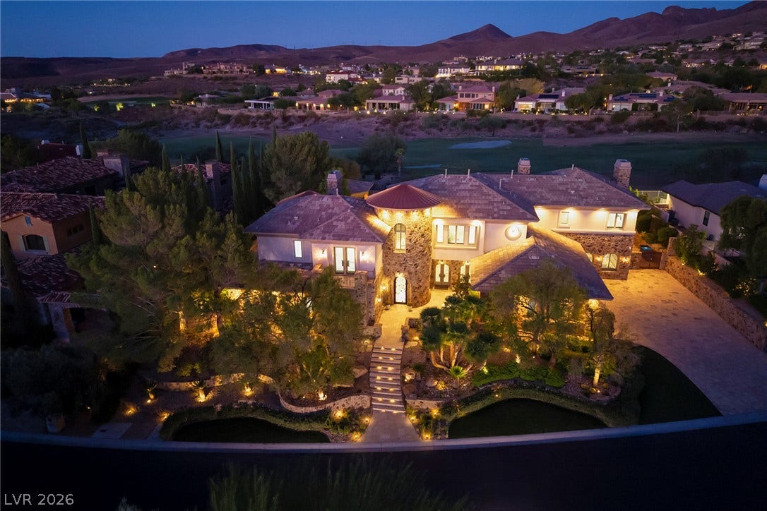 4 Ayden Drive, Henderson, NV 89052 Dramatic night illumination highlights this stone-clad estate nestled against a scenic mountain backdrop.