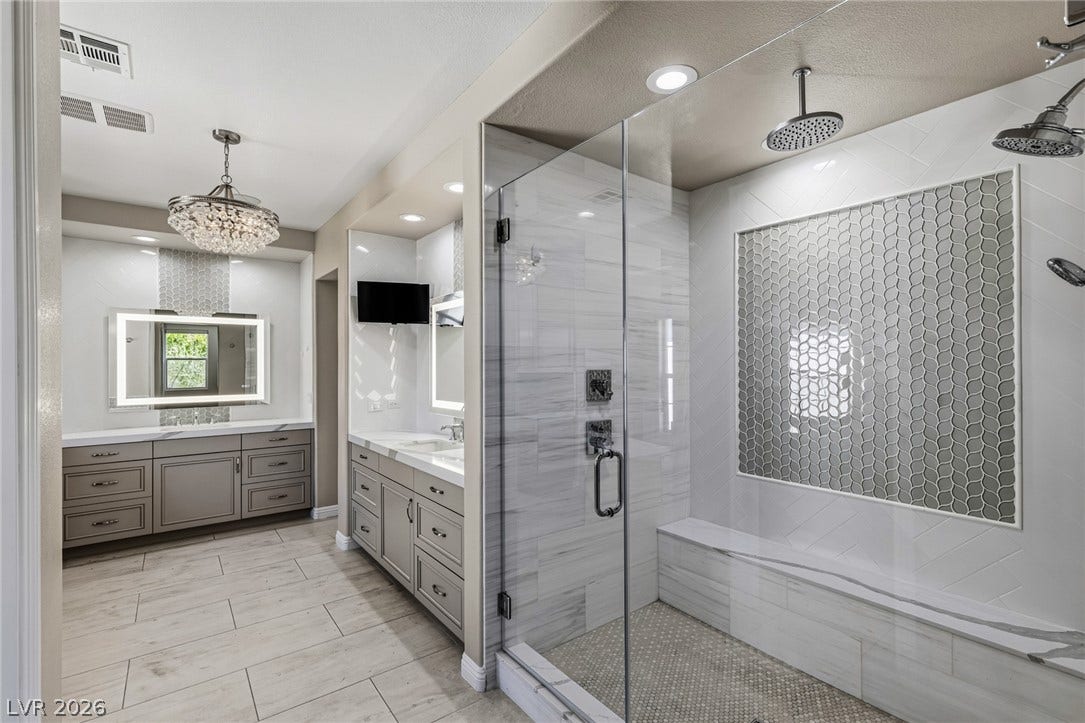 1201 Mersault Court, Las Vegas, NV 89144 An elegant glass-enclosed walk-in shower anchors this beautifully tiled primary bathroom with dual vanities.