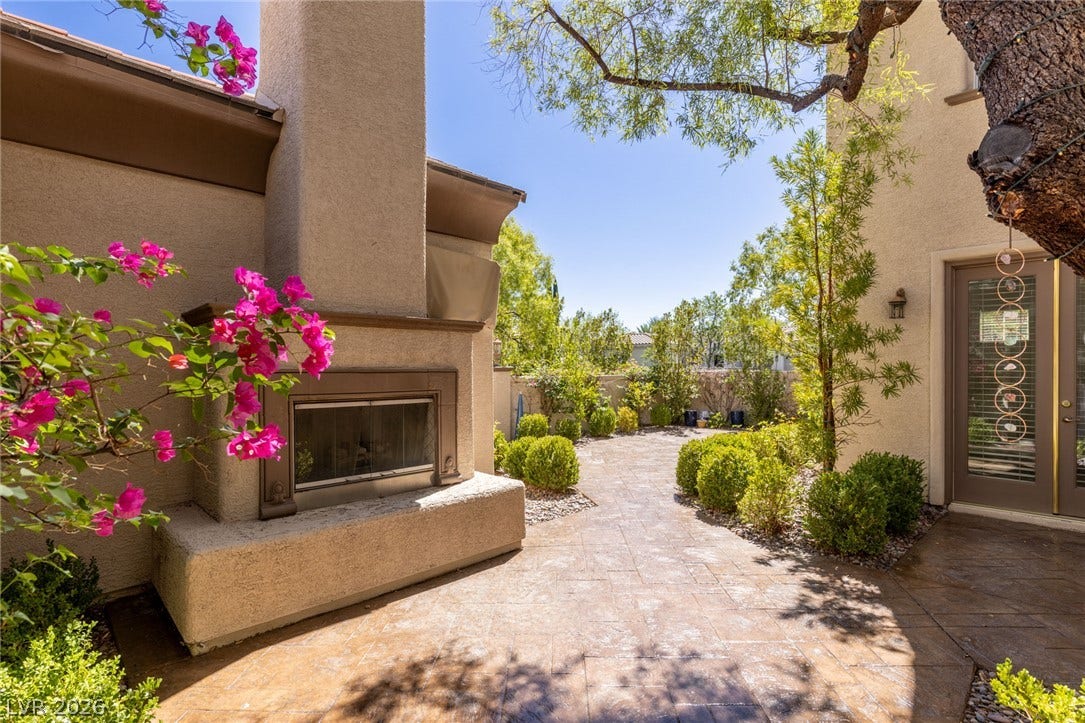 1201 Mersault Court, Las Vegas, NV 89144 An inviting outdoor fireplace highlights this beautifully paved patio surrounded by lush desert landscaping.
