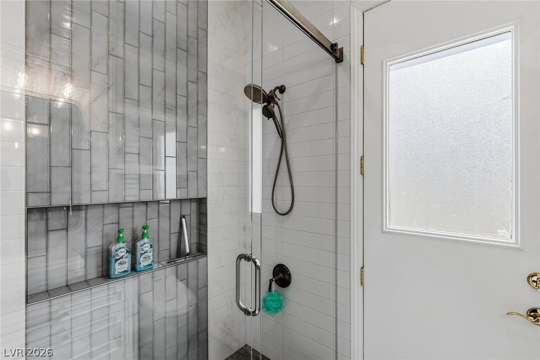 1201 Mersault Court, Las Vegas, NV 89144 Floor-to-ceiling tiles and a frameless glass door create a sleek modern shower design.
