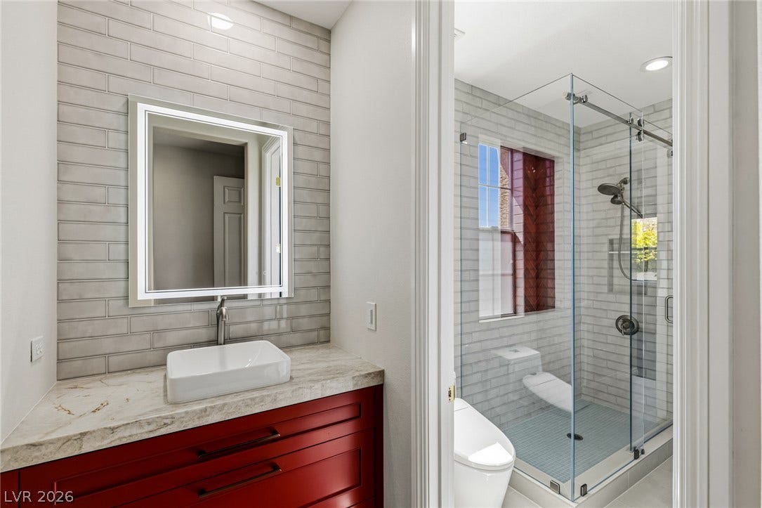 1201 Mersault Court, Las Vegas, NV 89144 A modern vanity with stone counters stands adjacent to a glass-enclosed walk-in shower.