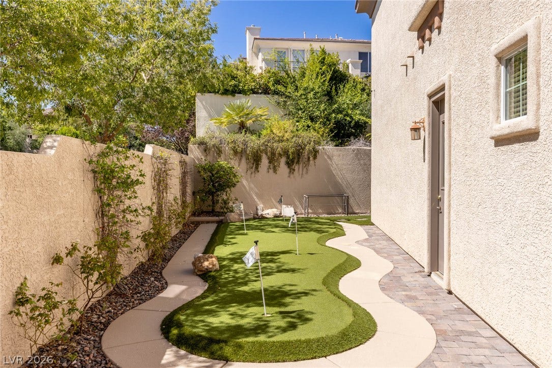 1201 Mersault Court, Las Vegas, NV 89144 Private outdoor courtyard features a custom putting green alongside paved walkways.
