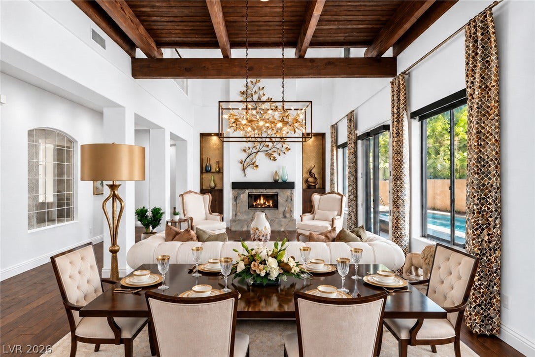 1201 Mersault Court, Las Vegas, NV 89144 Exposed wood beams and a stone fireplace anchor this grand open-concept living and dining area.