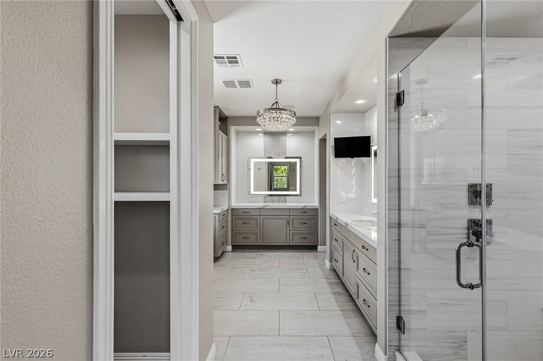 1201 Mersault Court, Las Vegas, NV 89144 A glass-enclosed shower highlights this modern bath area featuring large floor tiles and stone counters.