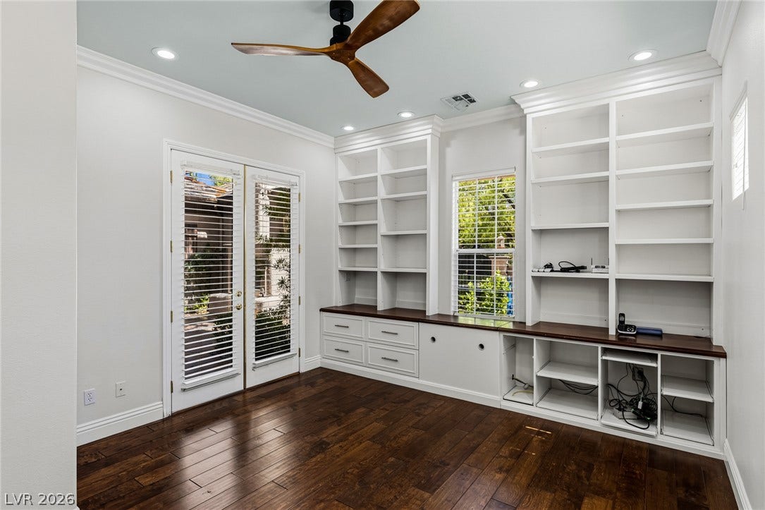 1201 Mersault Court, Las Vegas, NV 89144 Downstairs ensuite bedroom with courtyard walk out. Rich hardwood floors complement extensive custom built-in shelving and classic French doors.