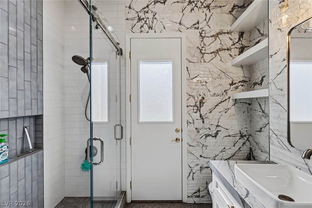 1201 Mersault Court, Las Vegas, NV 89144 Gleaming marble finishes and a glass-enclosed shower create a refined washroom experience.