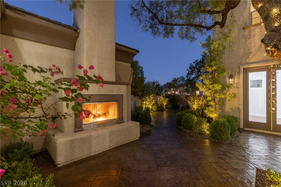 1201 Mersault Court, Las Vegas, NV 89144 An inviting outdoor fireplace highlights this beautifully paved patio area under the evening sky.