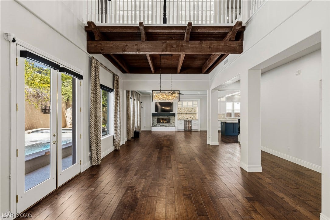 1201 Mersault Court, Las Vegas, NV 89144 Rich hardwood floors sweep across an open layout beneath a dramatic beamed ceiling.