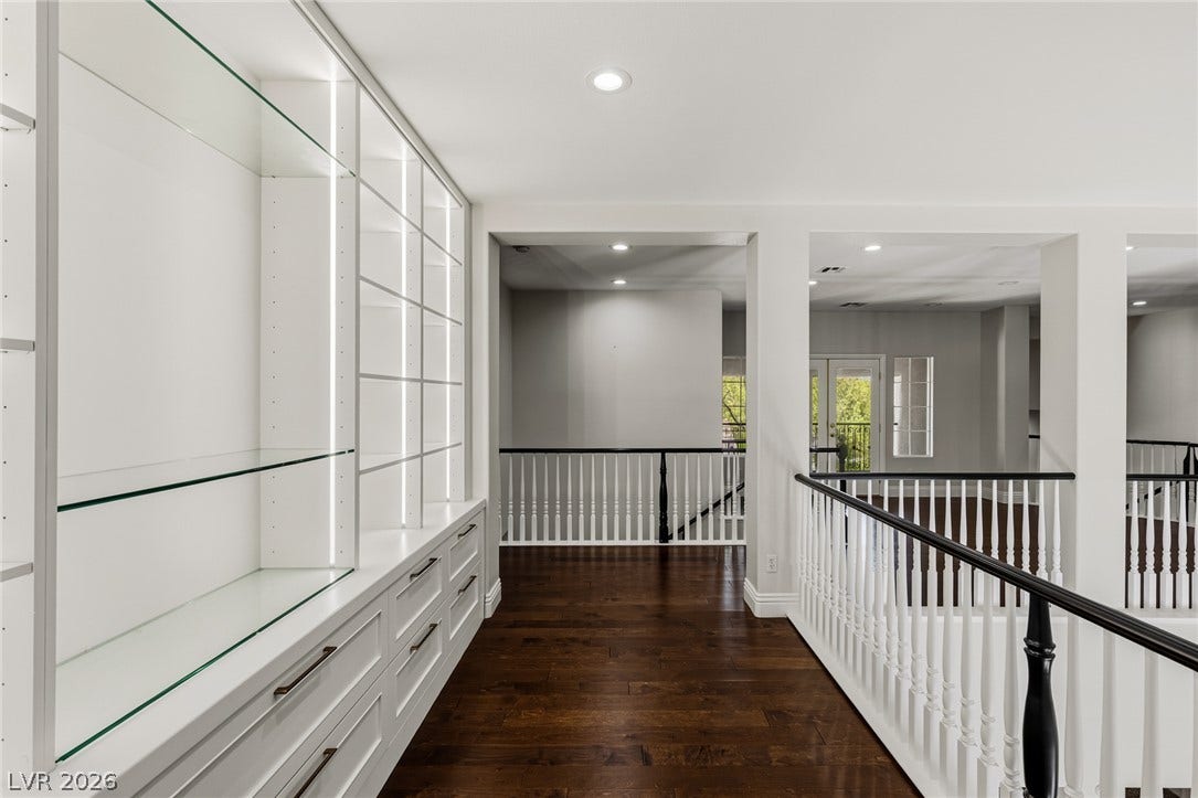 1201 Mersault Court, Las Vegas, NV 89144 Rich hardwood floors contrast beautifully with clean white custom built-ins and traditional banisters.