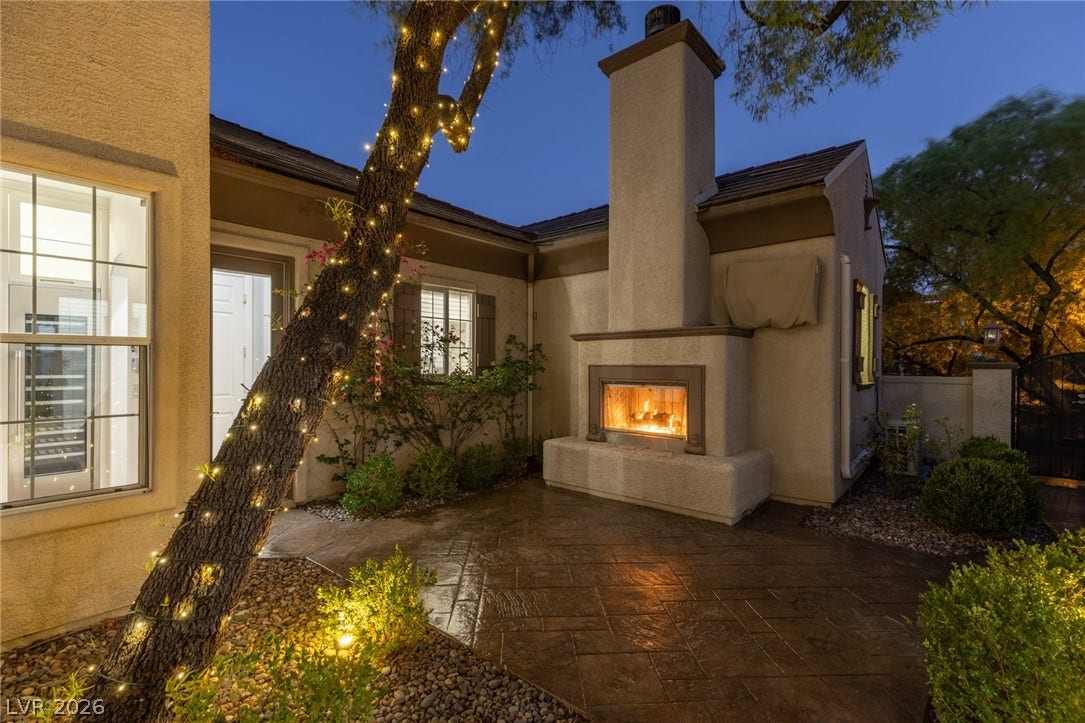 1201 Mersault Court, Las Vegas, NV 89144 An inviting stone patio offers a cozy fireplace nestled against the home's exterior wall.