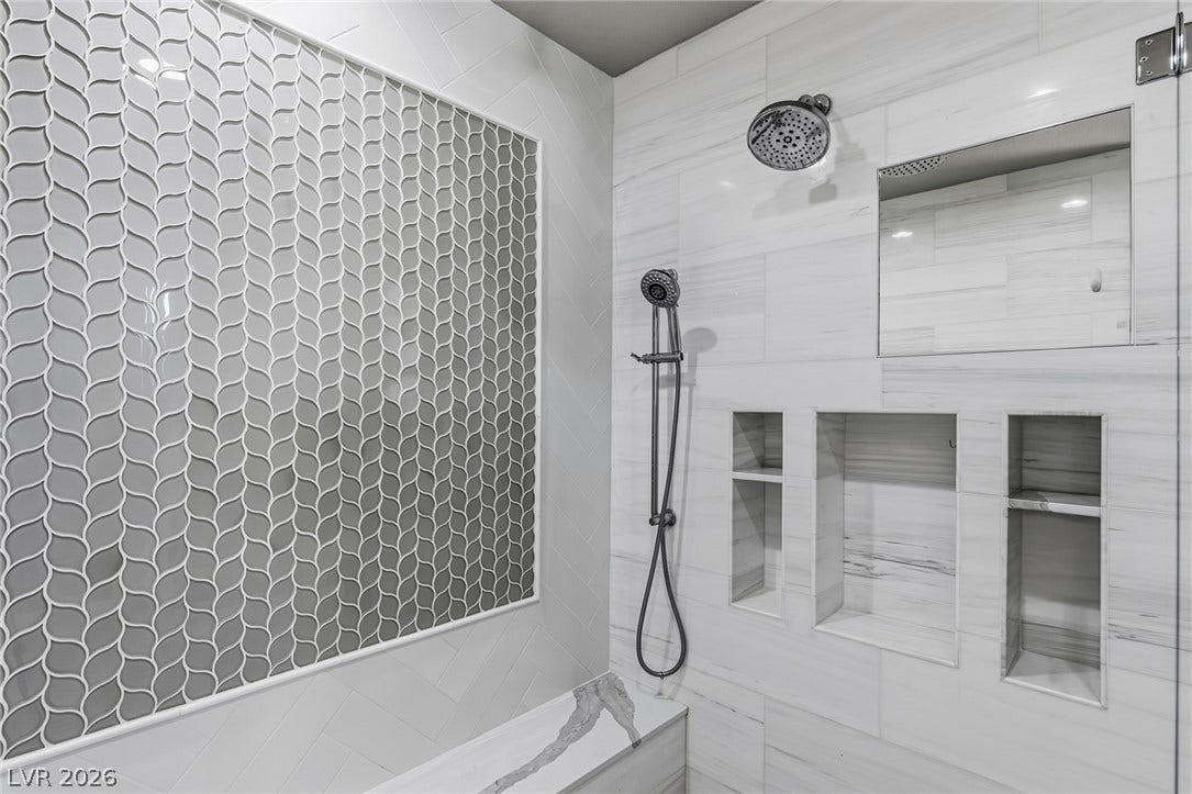 1201 Mersault Court, Las Vegas, NV 89144 Elegantly patterned tile and custom built-in niches elevate this modern walk-in shower.