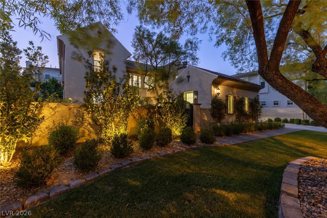 1201 Mersault Court, Las Vegas, NV 89144 Mature trees and professional lighting enhance the exterior facade of this multi-level home.