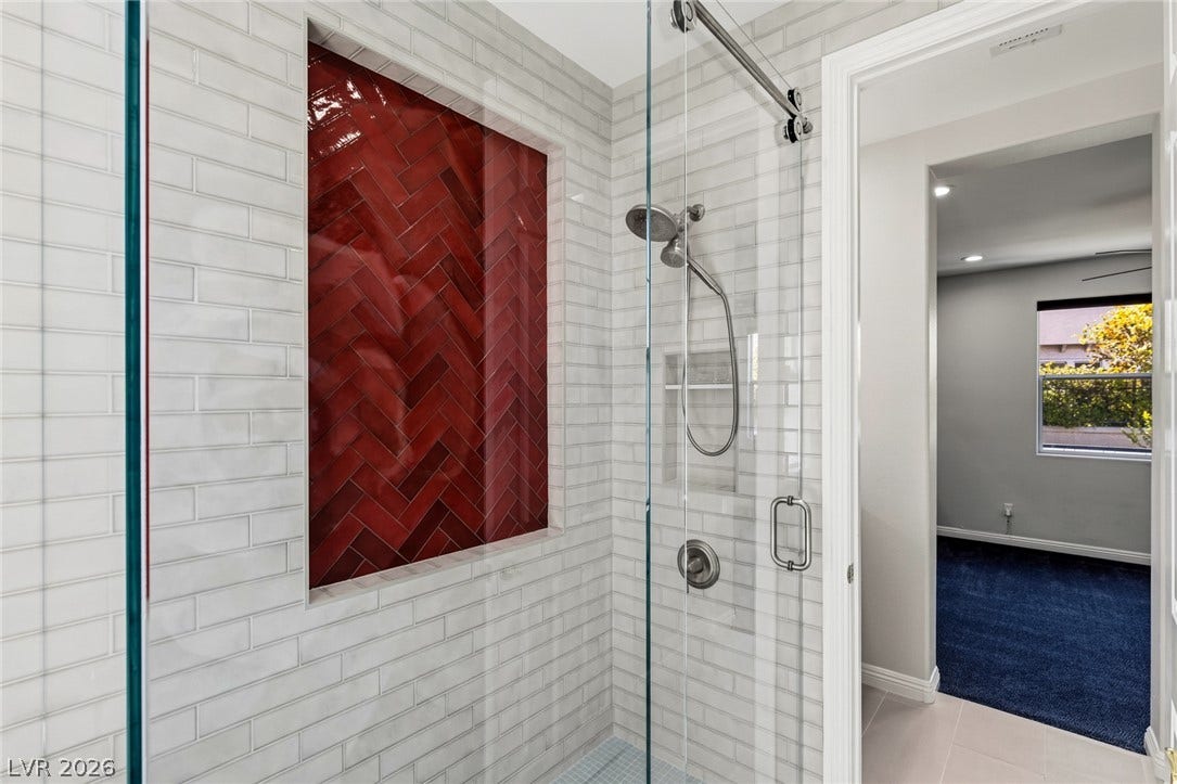 1201 Mersault Court, Las Vegas, NV 89144 Gleaming wall tiles and a glass door elevate this contemporary walk-in shower design.