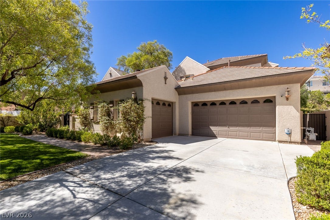 1201 Mersault Court, Las Vegas, NV 89144 An expansive concrete driveway leads to the three-car garage of this stucco-finished home.