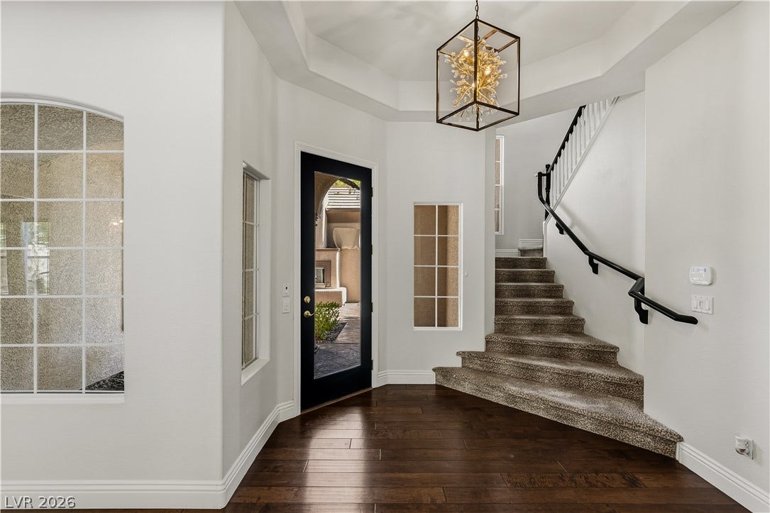 1201 Mersault Court, Las Vegas, NV 89144 Rich hardwood flooring complements the soaring tray ceiling and elegant staircase in this welcoming entryway.