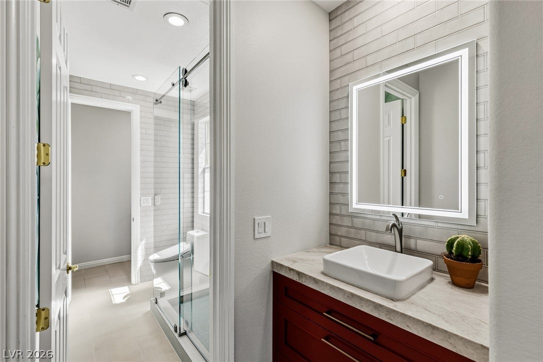 1201 Mersault Court, Las Vegas, NV 89144 Modern stone countertops and sleek tiling create a refined atmosphere in this bathroom.