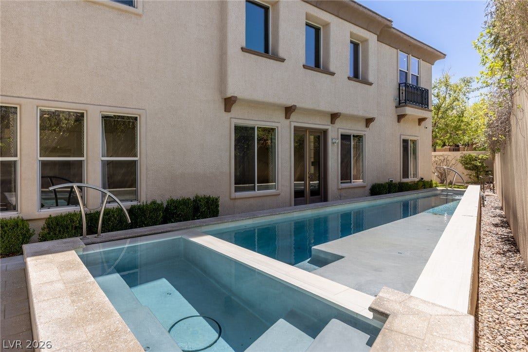 1201 Mersault Court, Las Vegas, NV 89144 A sleek lap pool and integrated spa sit alongside the stucco exterior of this residence.
