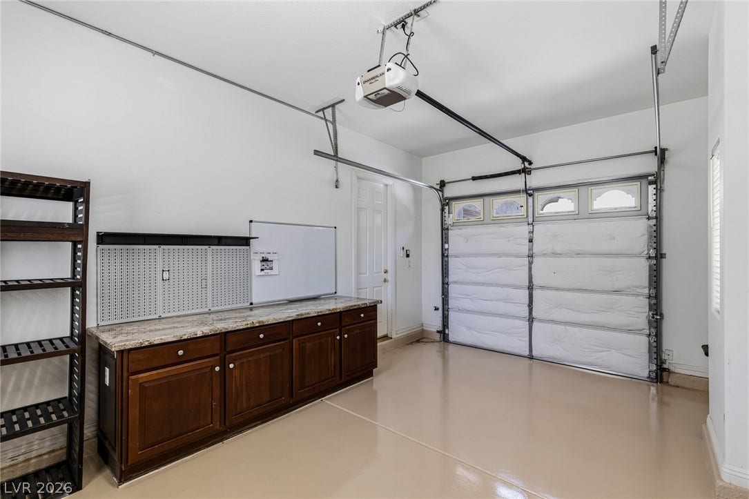 1201 Mersault Court, Las Vegas, NV 89144 A spacious garage features smooth finished flooring and integrated cabinetry with stone countertops.