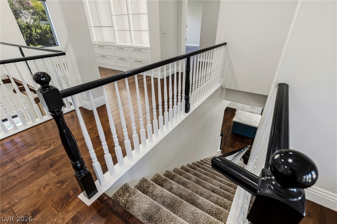 1201 Mersault Court, Las Vegas, NV 89144 Rich wood flooring and classic railings anchor this elegant transitional staircase landing.