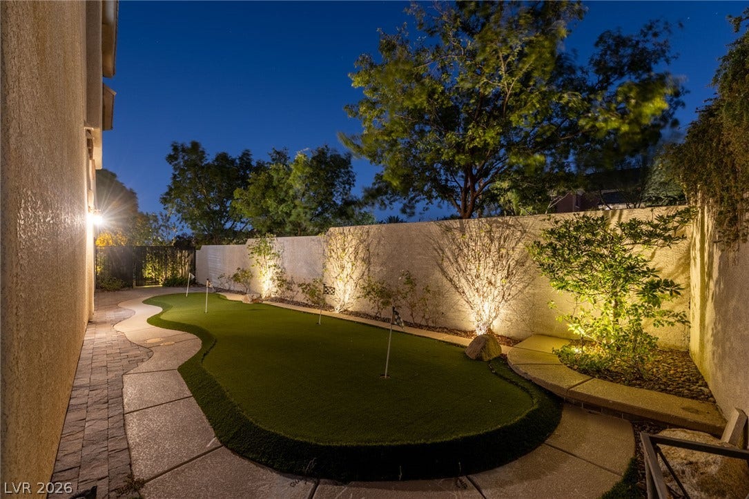 1201 Mersault Court, Las Vegas, NV 89144 An illuminated private putting green winds alongside the home under the evening sky.