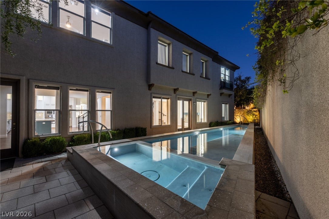 1201 Mersault Court, Las Vegas, NV 89144 An integrated spa and lap pool parallel a stucco exterior under twilight skies.