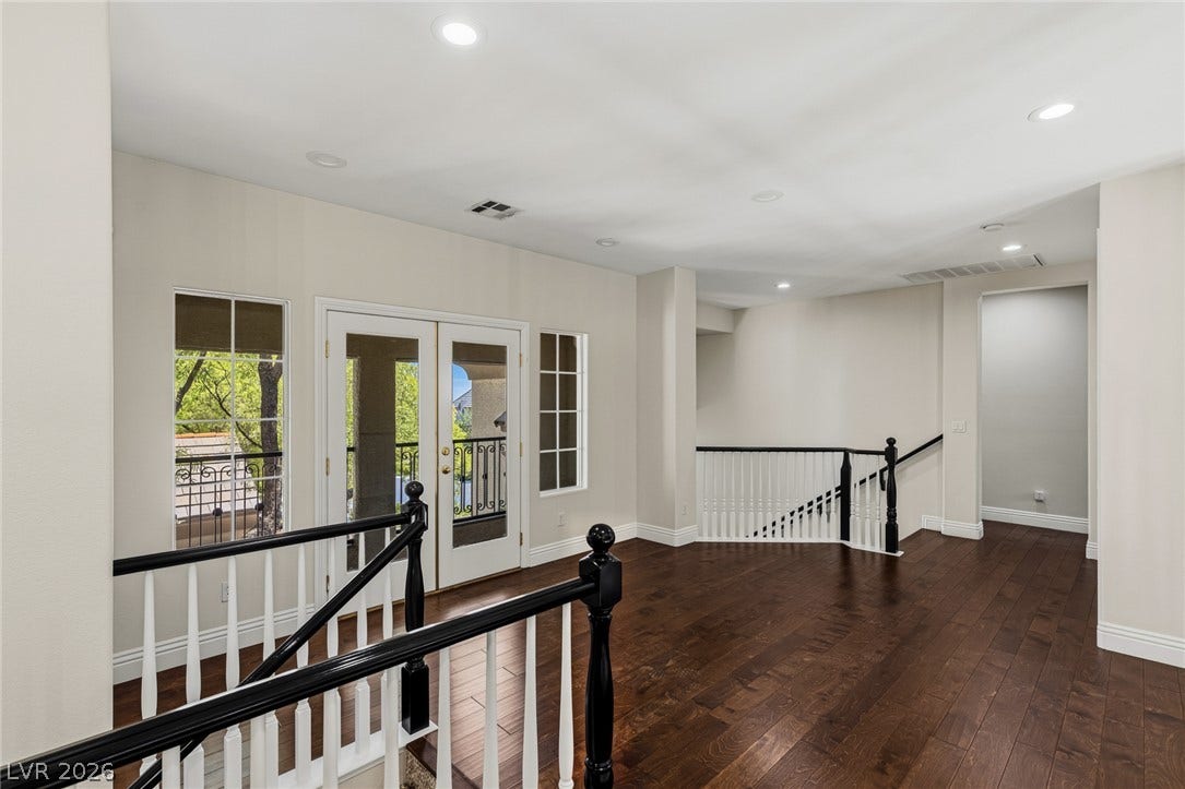 1201 Mersault Court, Las Vegas, NV 89144 Rich hardwood floors and classic banisters define this spacious upper-level landing with balcony access.