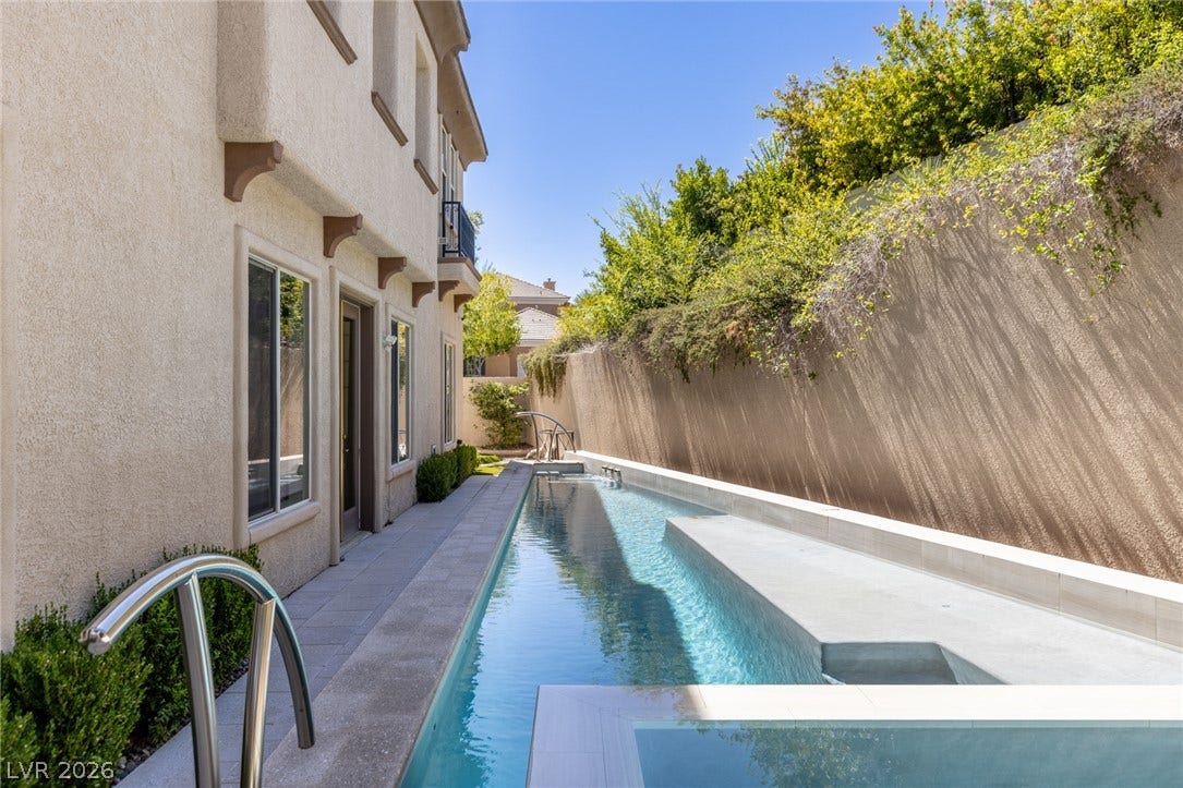 1201 Mersault Court, Las Vegas, NV 89144 A sleek lap pool runs alongside the stucco exterior under clear blue skies.