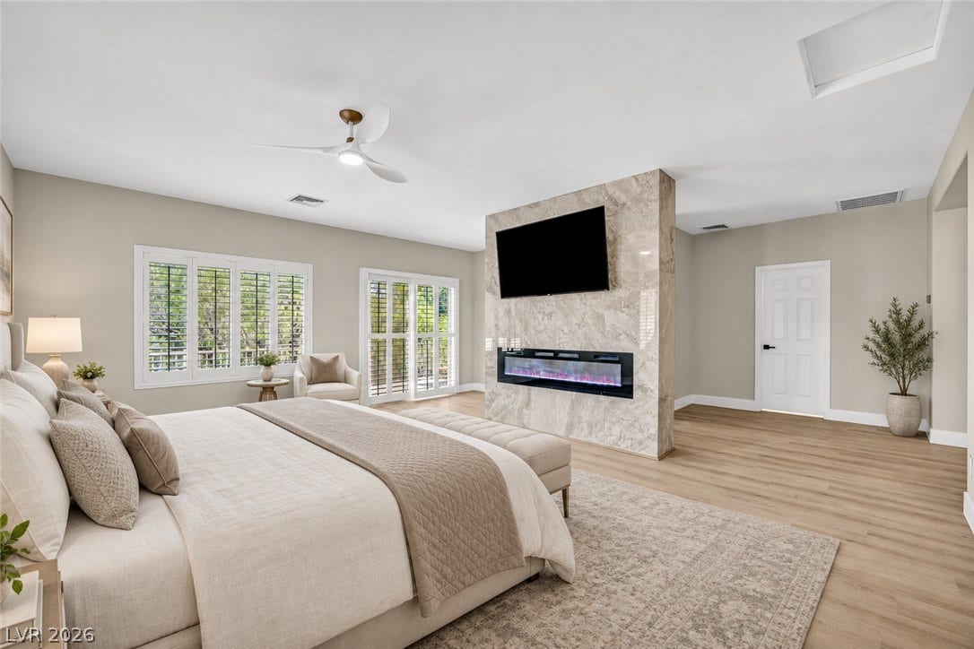 17 Winding Road, Henderson, NV 89052 Virtually Staged.
A modern fireplace on a stone partition accents this airy bedroom with light wood flooring.