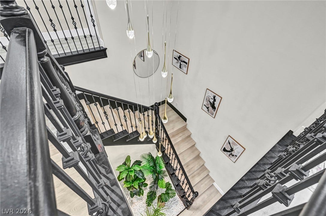 17 Winding Road, Henderson, NV 89052 Virtually staged. Dramatic multi-level stairs wrap around a central light installation descending to wood flooring below.