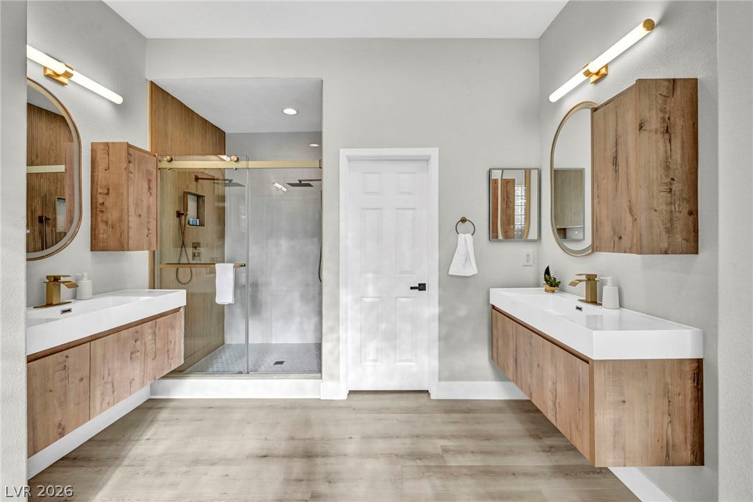 17 Winding Road, Henderson, NV 89052 Double vanities with warm wood tones frame a sleek glass walk-in shower.