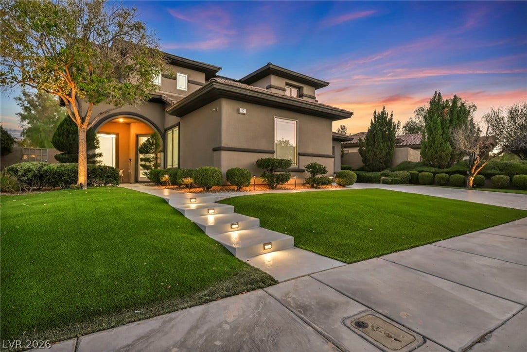 17 Winding Road, Henderson, NV 89052 Illuminated concrete steps lead through manicured green lawns to a contemporary arched entryway.