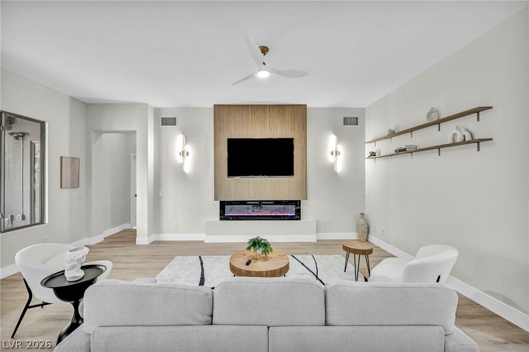 17 Winding Road, Henderson, NV 89052 Virtually staged.
A modern fireplace with custom wood paneling anchors this open-plan living space featuring hardwood floors.