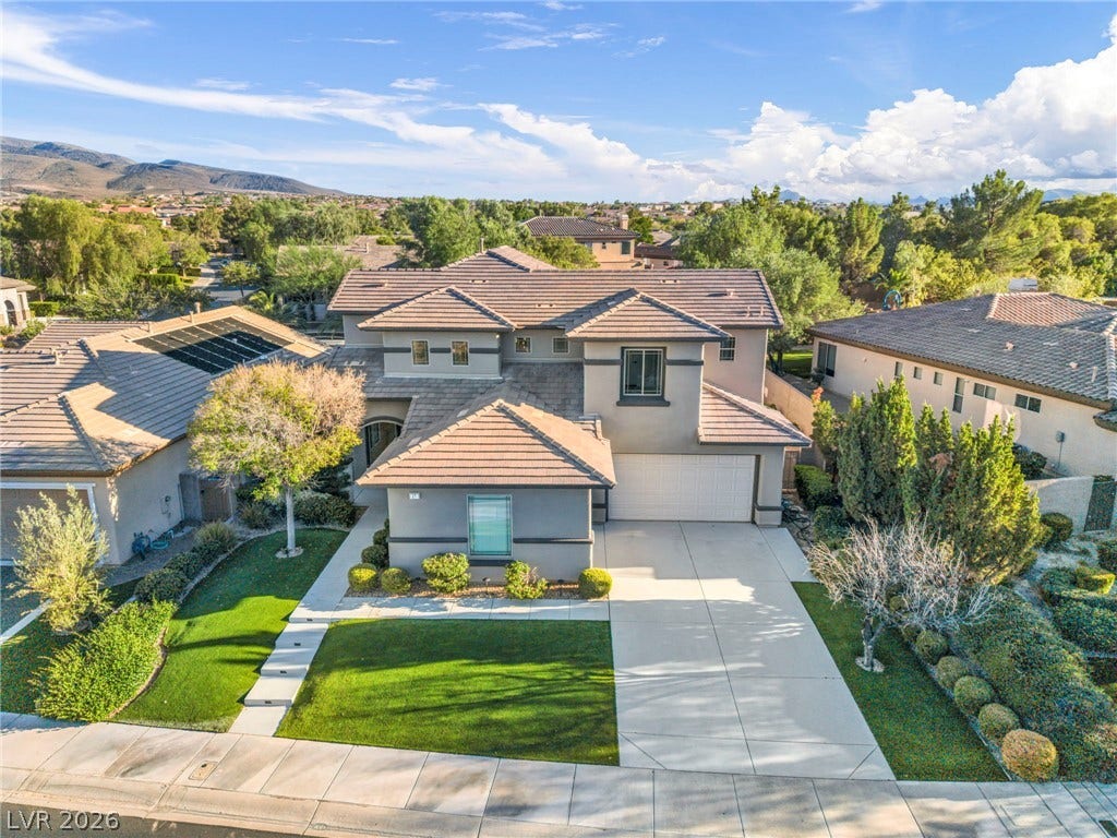 17 Winding Road, Henderson, NV 89052 A spacious driveway and neat landscaping front this multi-level home under a bright sky.