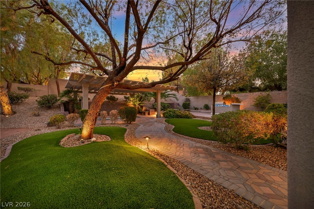 17 Winding Road, Henderson, NV 89052 A stone paver pathway winds through manicured turf toward a backyard pergola.