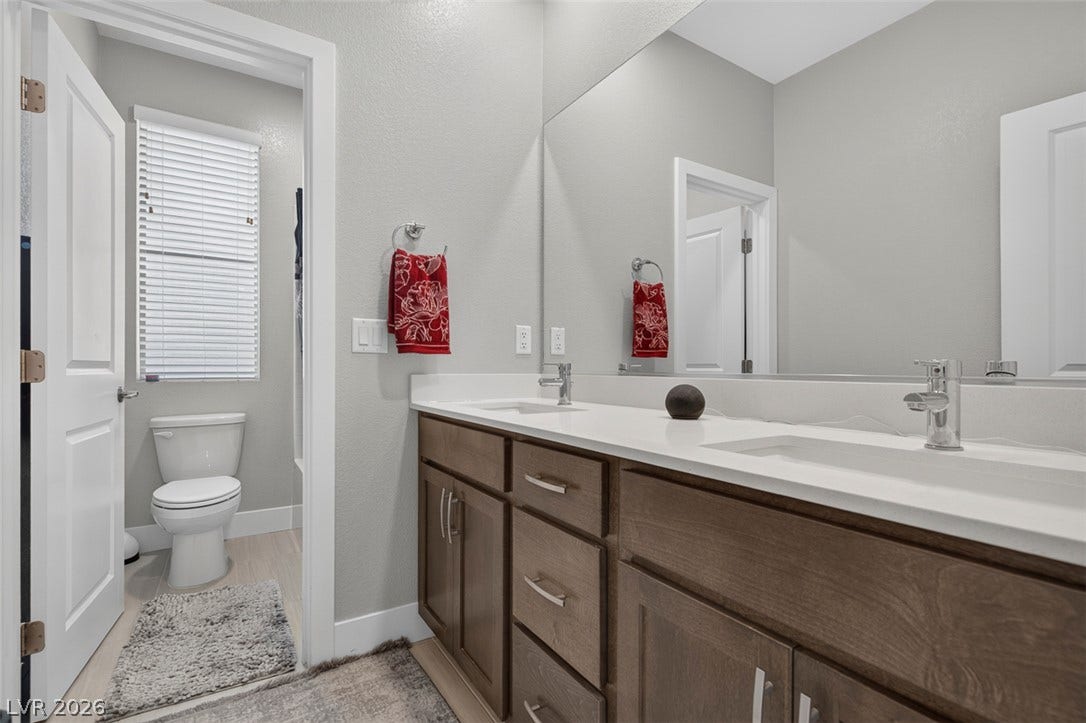 6849 Desert Finch Street, North Las Vegas, NV 89084 A spacious double vanity features clean countertops and ample wooden cabinetry.