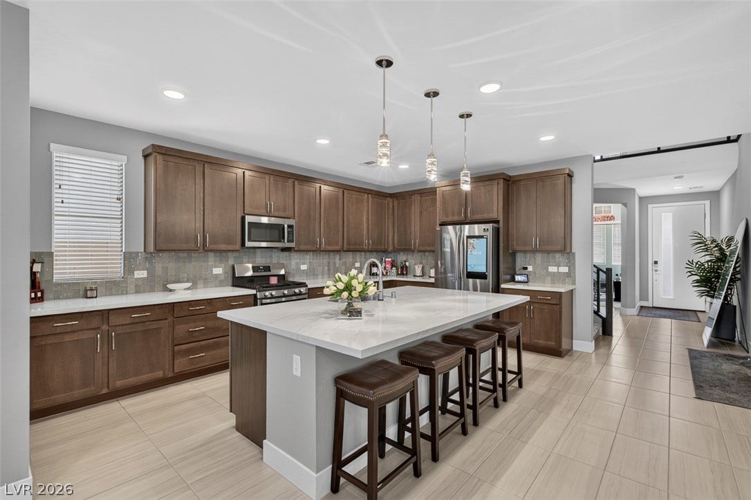 6849 Desert Finch Street, North Las Vegas, NV 89084 Gleaming stone countertops and wood cabinetry define this open culinary space with a large island.