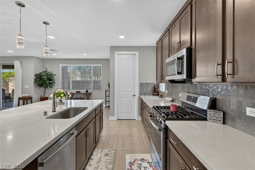 6849 Desert Finch Street, North Las Vegas, NV 89084 Gleaming stone countertops and modern cabinetry define this spacious open kitchen layout.