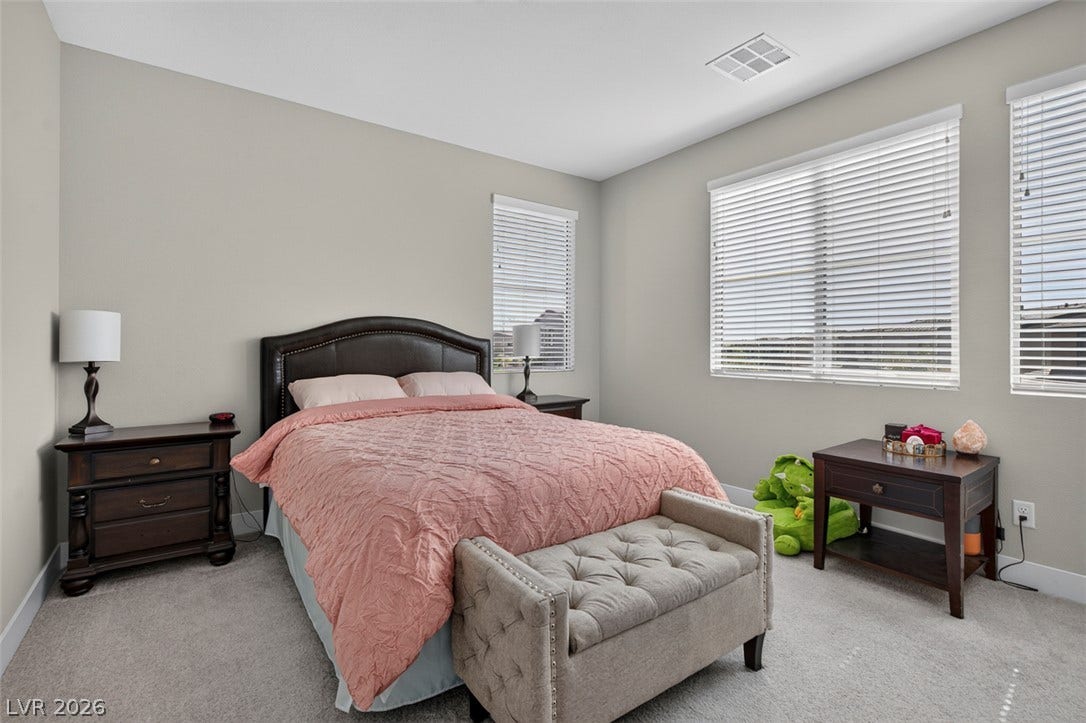 6849 Desert Finch Street, North Las Vegas, NV 89084 Bedroom with ensuite bathroom. Plentiful natural light fills this bedroom featuring neutral-toned walls and soft carpeting throughout.