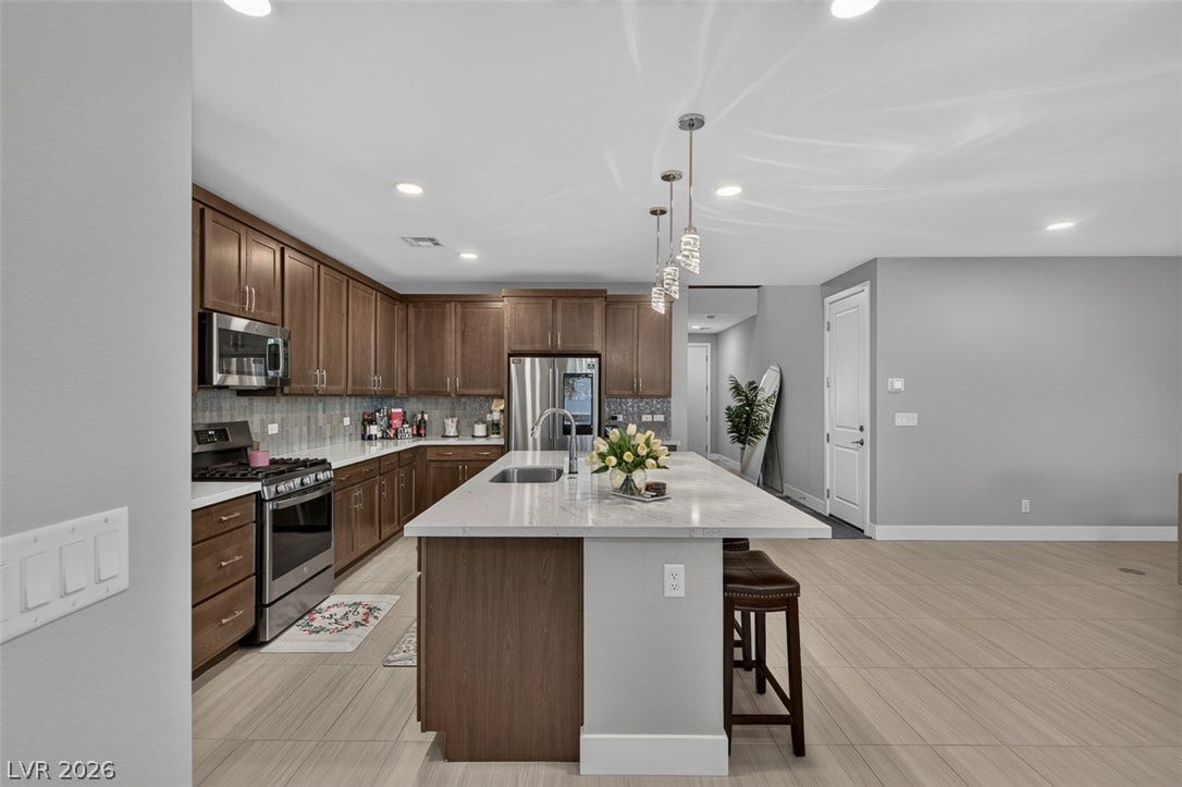 6849 Desert Finch Street, North Las Vegas, NV 89084 Gleaming stone countertops and classic wood cabinetry anchor this spacious culinary space.