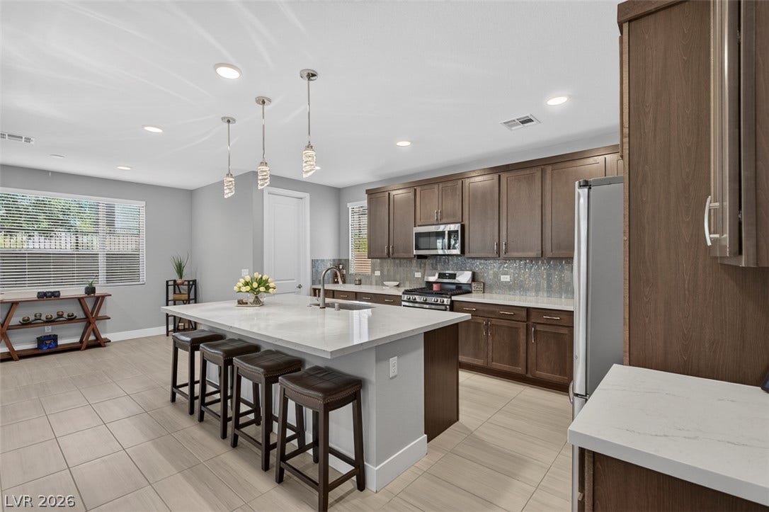 6849 Desert Finch Street, North Las Vegas, NV 89084 Rich wood cabinetry contrasts beautifully with pale stone countertops in this modern culinary space.