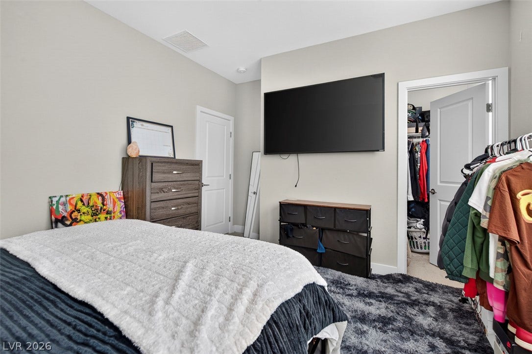 6849 Desert Finch Street, North Las Vegas, NV 89084 A spacious bedroom offers plush neutral carpeting and convenient access to a walk-in closet.