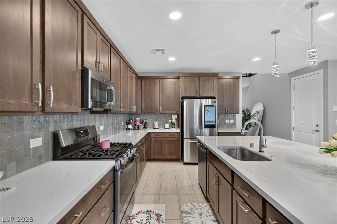 6849 Desert Finch Street, North Las Vegas, NV 89084 Rich wood cabinetry contrasts beautifully with sleek stone countertops in this modern culinary space.