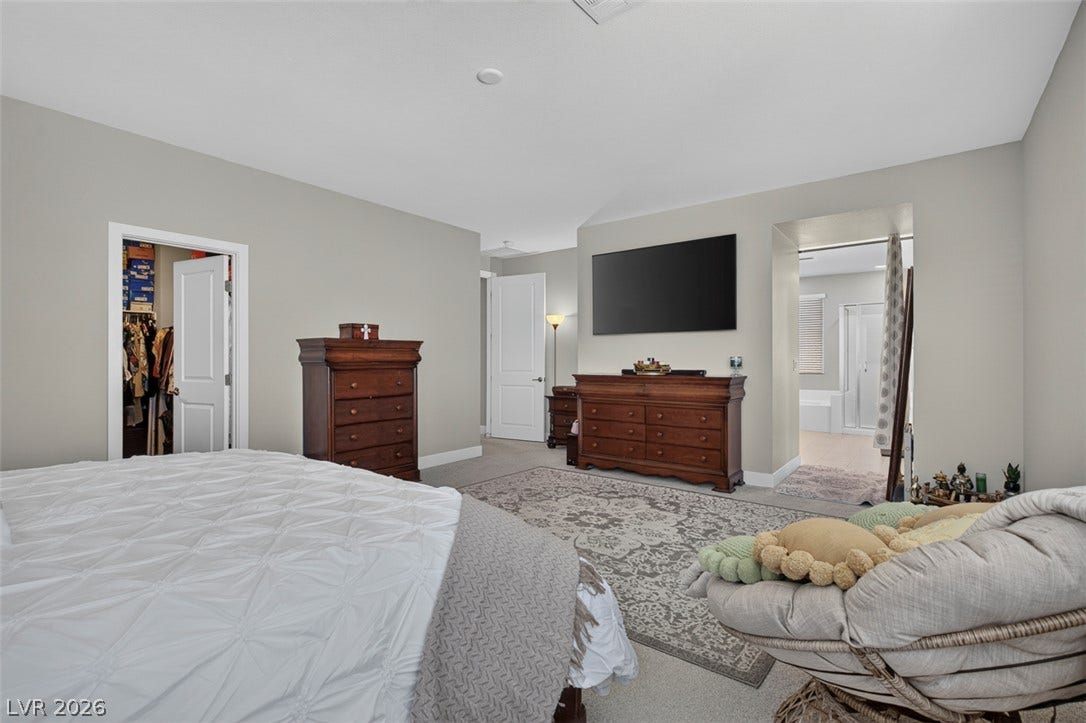6849 Desert Finch Street, North Las Vegas, NV 89084 Plush carpeting anchors this spacious bedroom featuring an attached private bath and a walk-in closet.