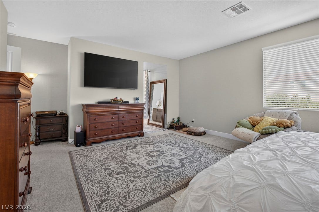 6849 Desert Finch Street, North Las Vegas, NV 89084 A spacious bedroom offers plush neutral carpeting and a wide window with integrated blinds.