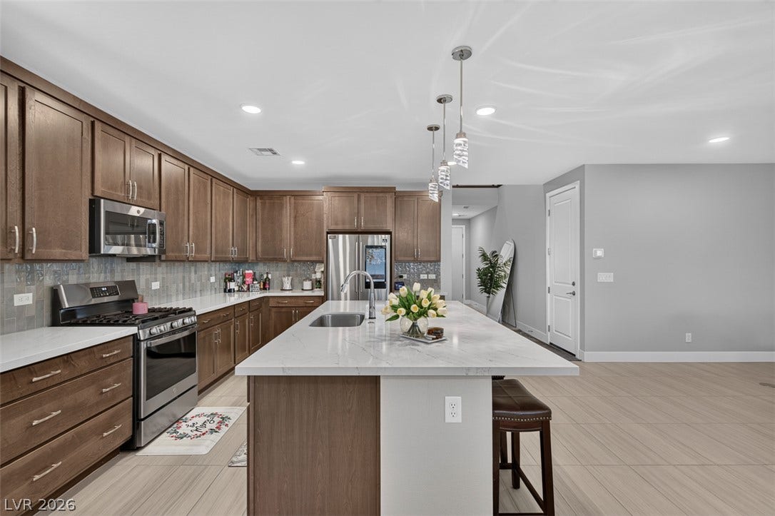 6849 Desert Finch Street, North Las Vegas, NV 89084 Gleaming stone countertops and warm wood cabinetry anchor this spacious culinary space.